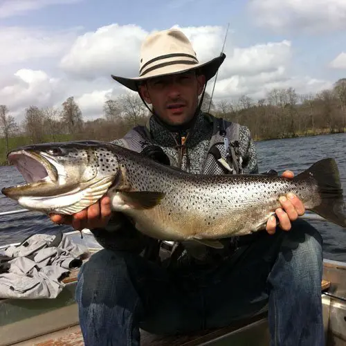 Franck Coudière guide de pêche à la mouche posant avec une belle truite du Lac de la Landie