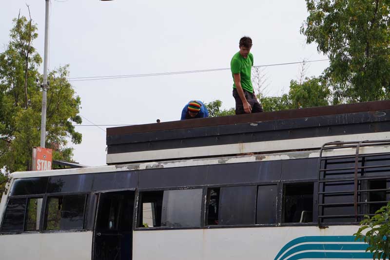 Nico accroche les vélos sur le toit du bus durant notre déplacement en Inde