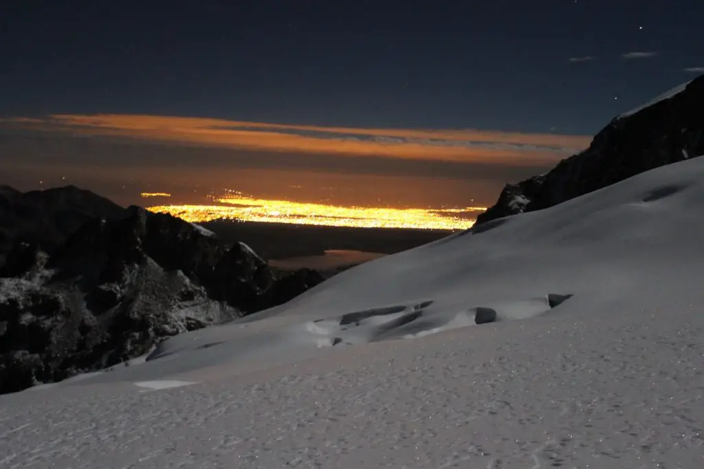 Tandis que nous grimpons dans la glace, les lumières de la ville apparaissent déjà en fond