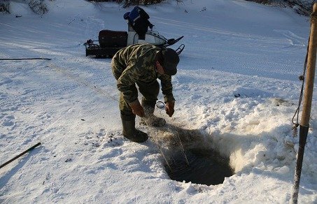 Après avoir percé la glace, Sacha relève le filet lors du voyage à vélo sur le fleuve Amour en Sibérie 