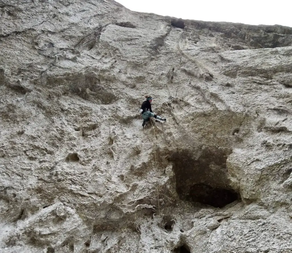 Marion en train de grimper un tour de cou en guise de bandeau durant une session escalade en hiver