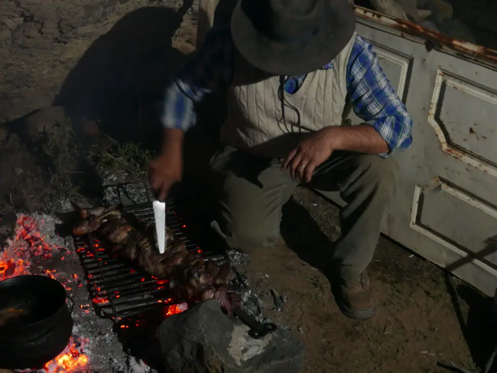 le chef cuistot gaucho surveille la cuisson de l'asado à la frontière chilienne en argentine