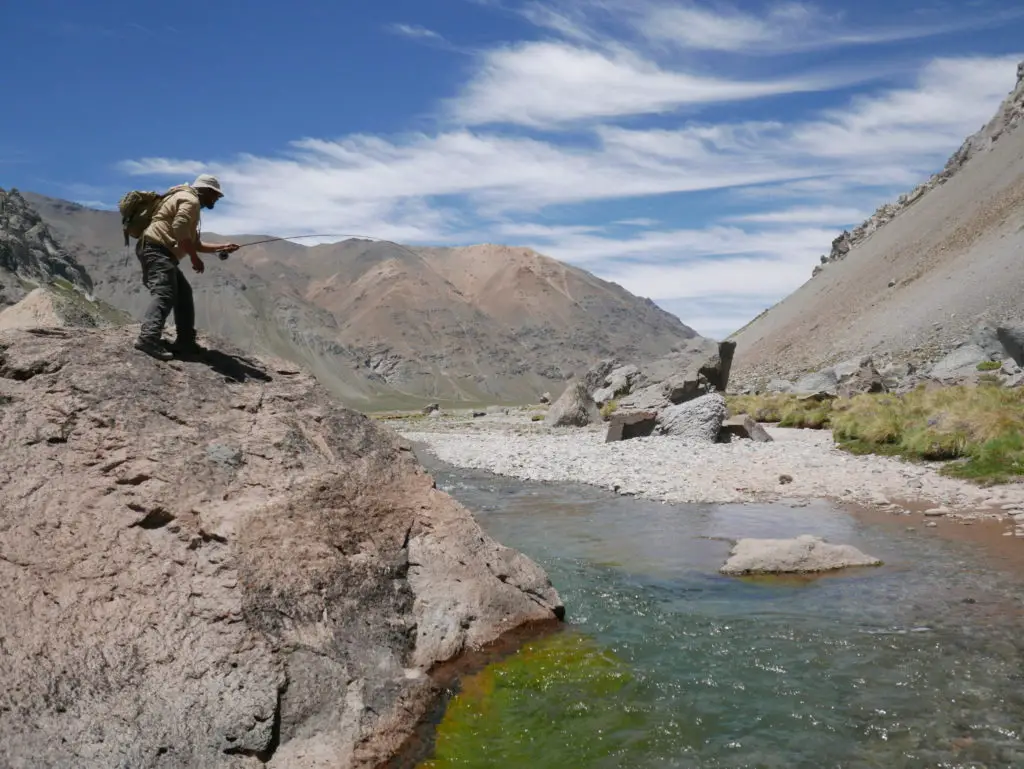 Zurdo sur un rocher bataille avec une belle truite de la rivière el cura en valle noble en argentine