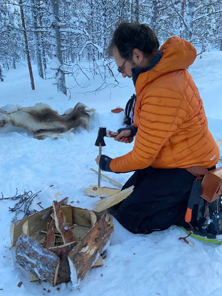 couper du bois avec une hache pour un feu sur la neige