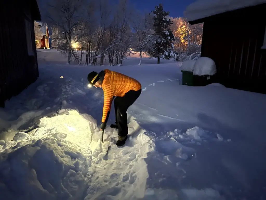 déneigement à la frontale go'lum d'une allée de neige à la pelle en suède