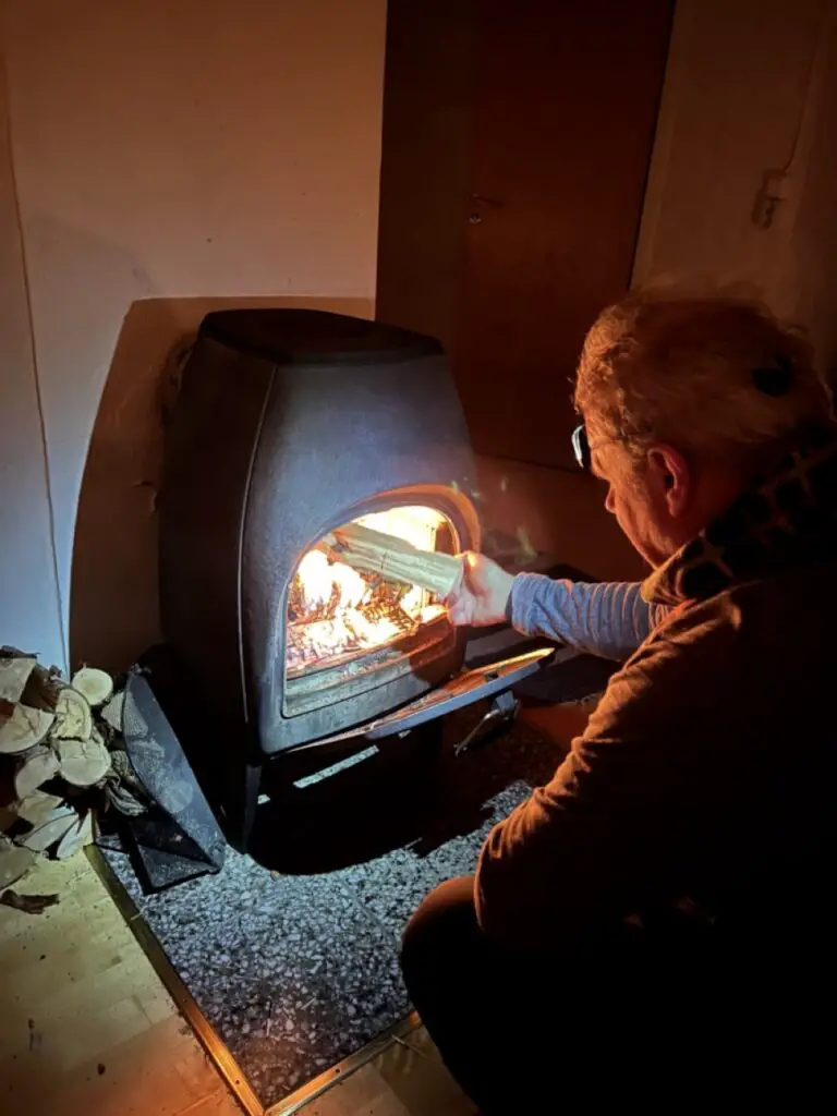 Gérard Longuet préparant le feu du poêle dans une cabane en suède