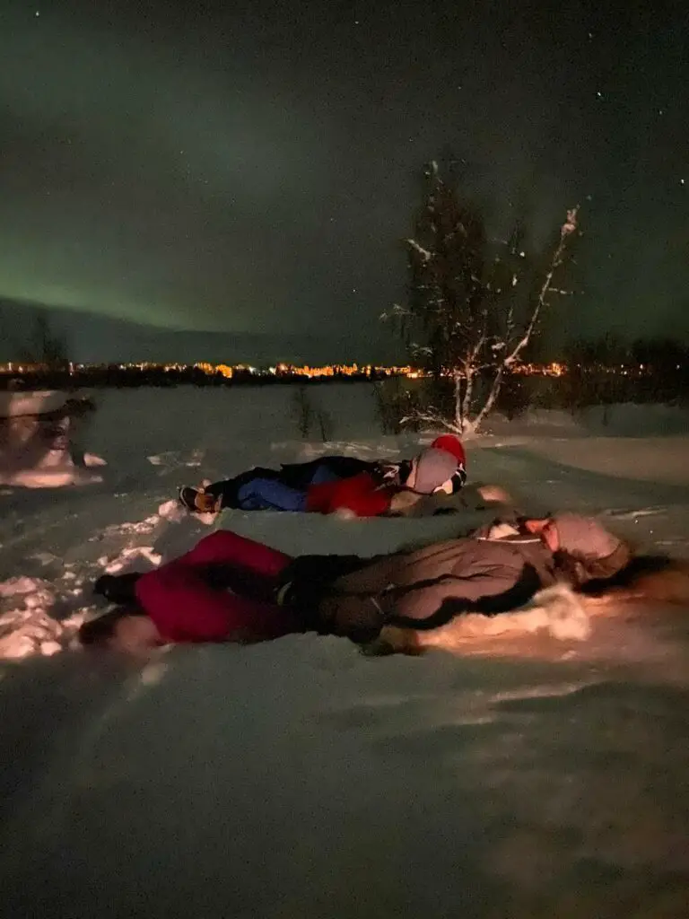 Observation des aurores boréales allongée sur une peau de rennes sur la neige