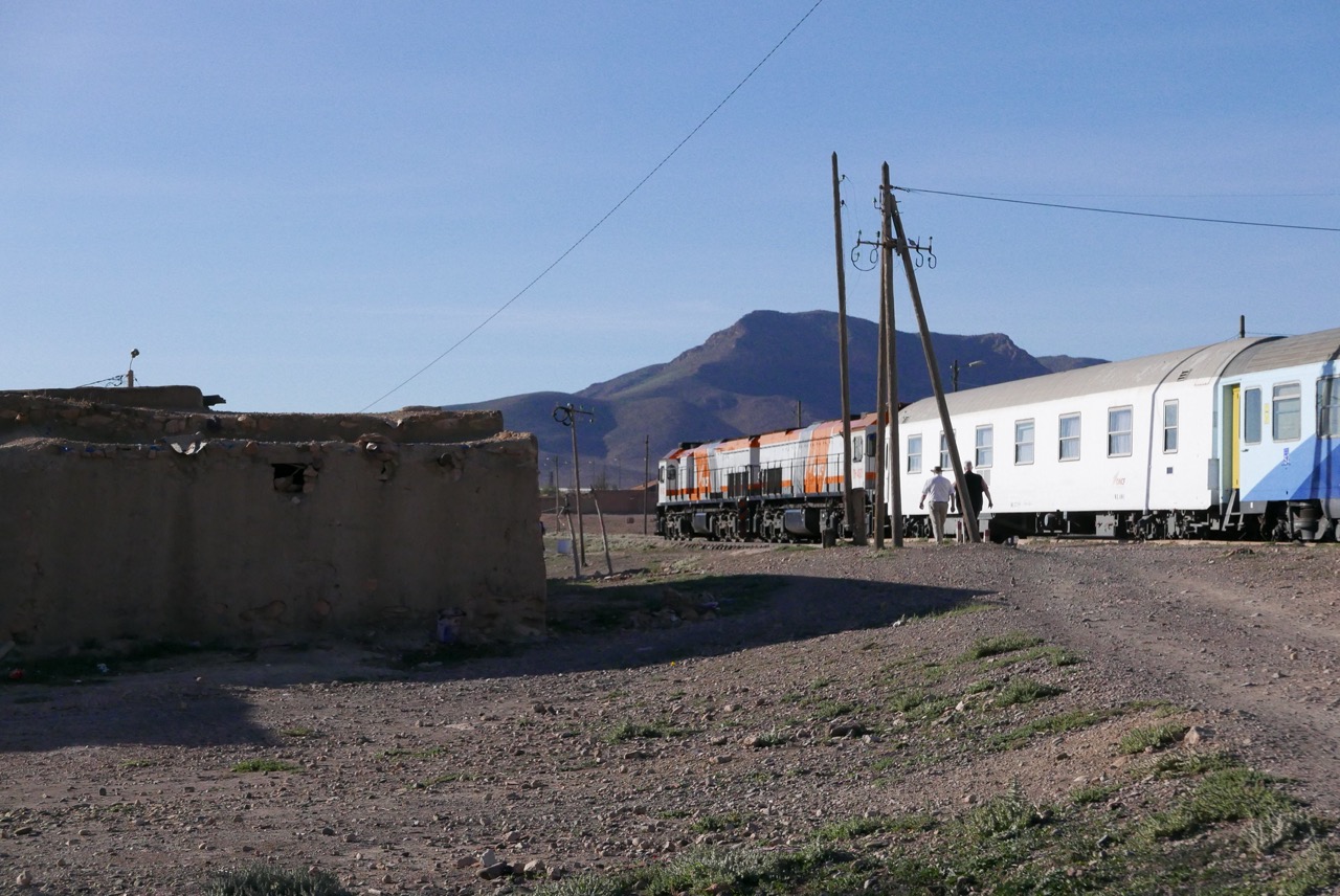 Train du désert traversant un village marocain