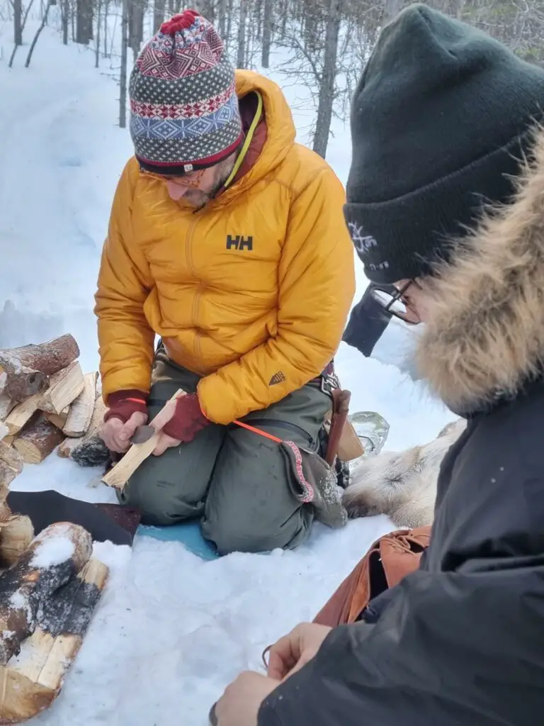 couper du bois pour préparer un feu sur la neige en laponie