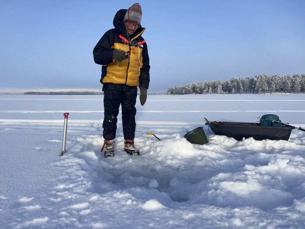 Pêche blanche en laponie suédoise à -30 degrés bien au chaud dans sa doudoune the north face
