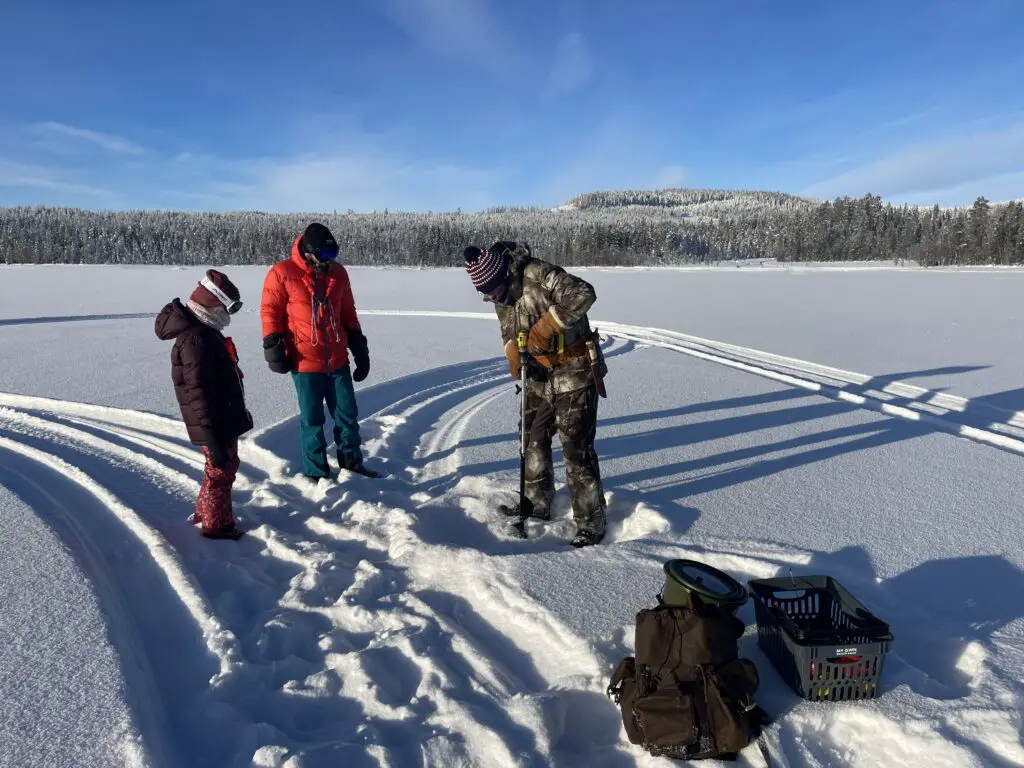 forage dans la glace du lac pour journée pêche blanche en laponie